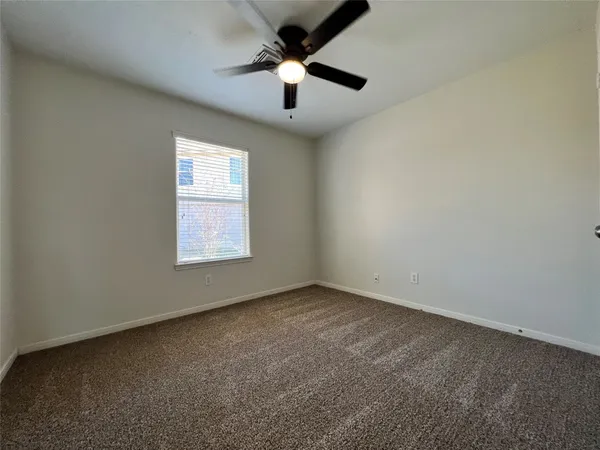 an empty room with a window and a ceiling fan