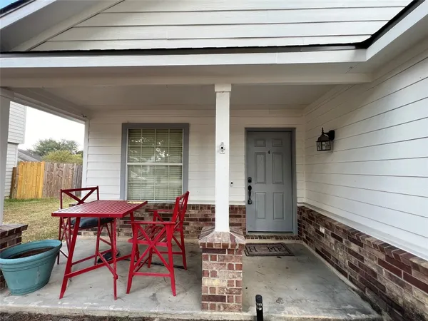a patio with table and chairs and potted plants