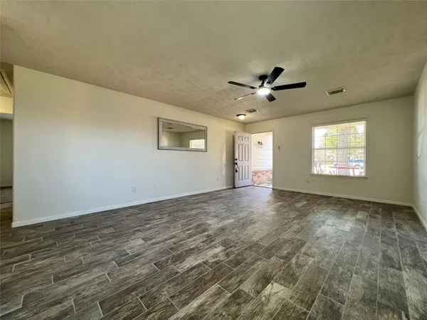 an empty room with windows and a ceiling fan