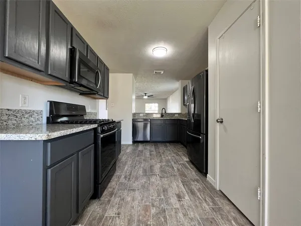 a large kitchen with stainless steel appliances granite countertop a refrigerator and a stove top oven