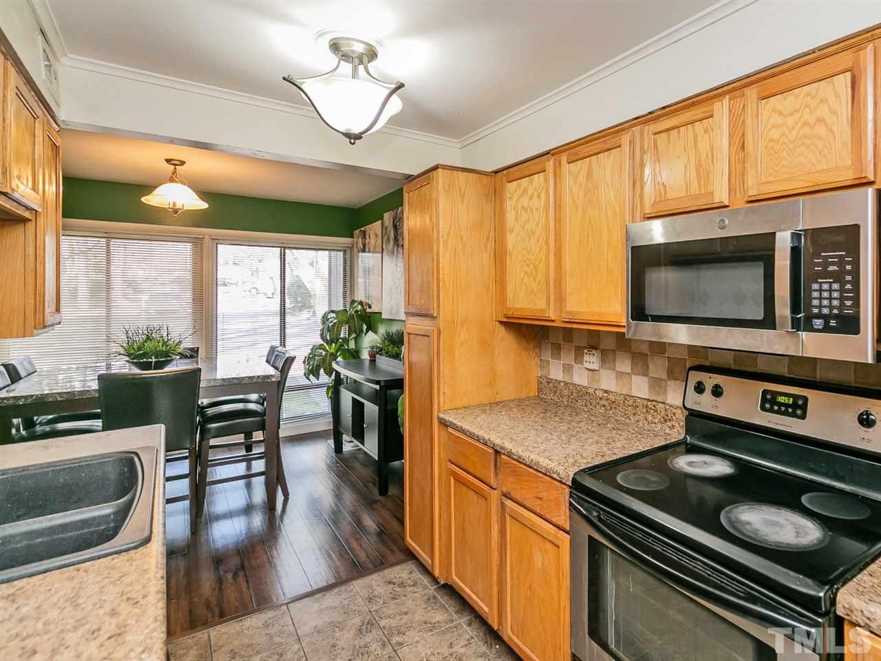 1722 Quail Ridge Road Raleigh, NC 27609 - Photo 3 of 28 a kitchen with a stove a sink a microwave a dining table and chairs