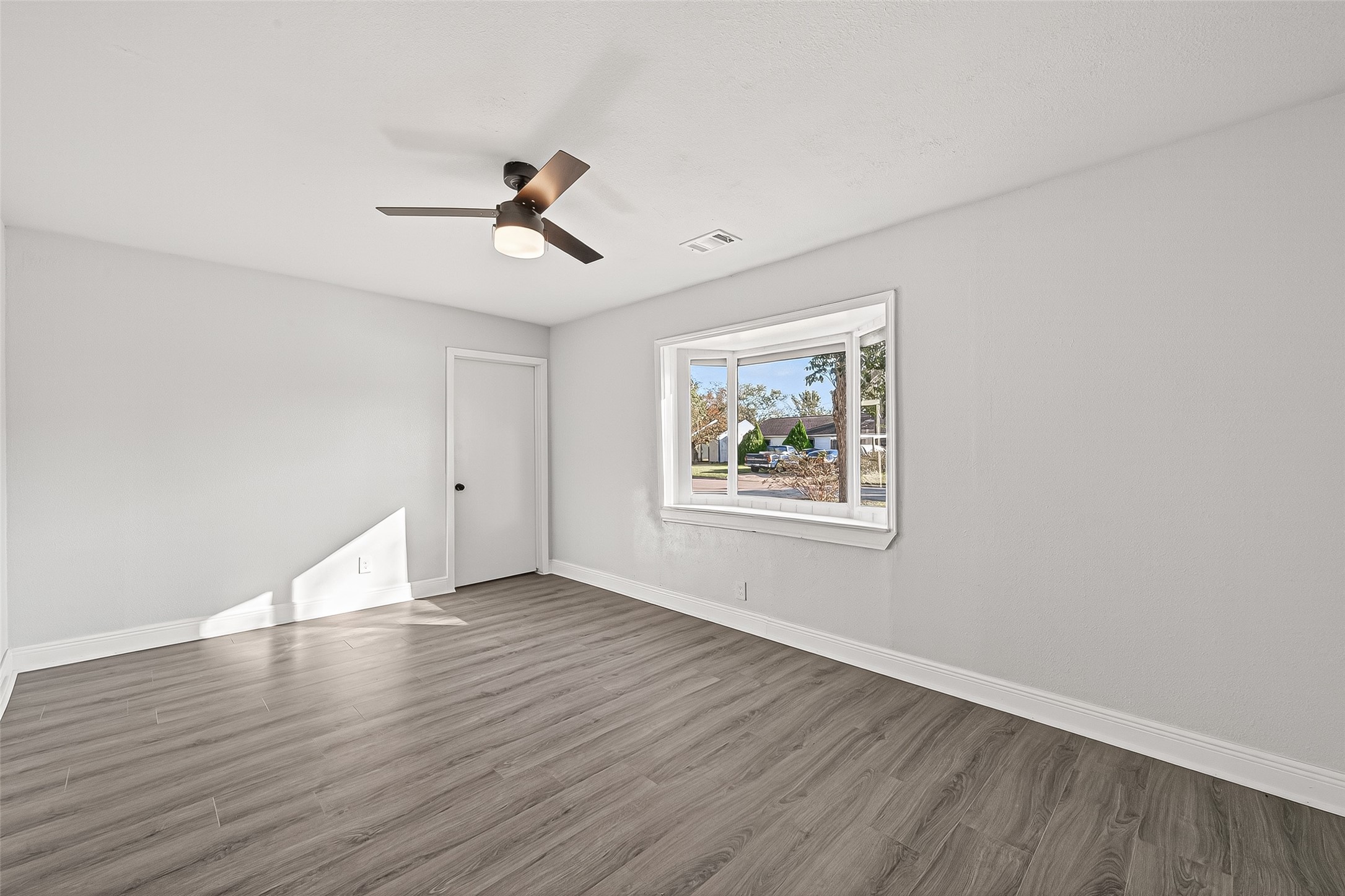 4729 Paradise Lane Houston, TX 77048 - Photo 11 of 43 an empty room with wooden floor ceiling fan and windows