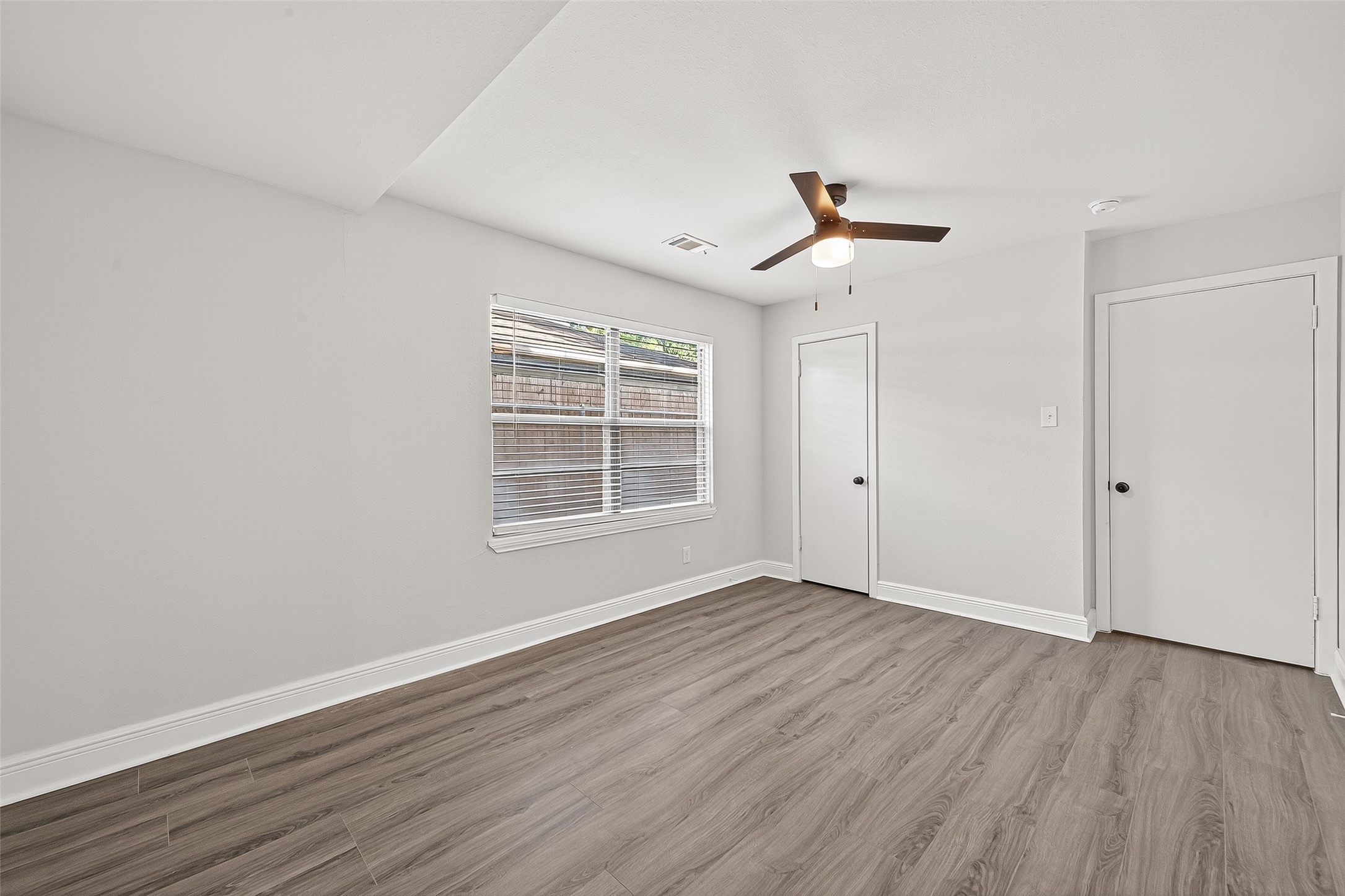 4729 Paradise Lane Houston, TX 77048 - Photo 15 of 43 an empty room with wooden floor ceiling fan and windows