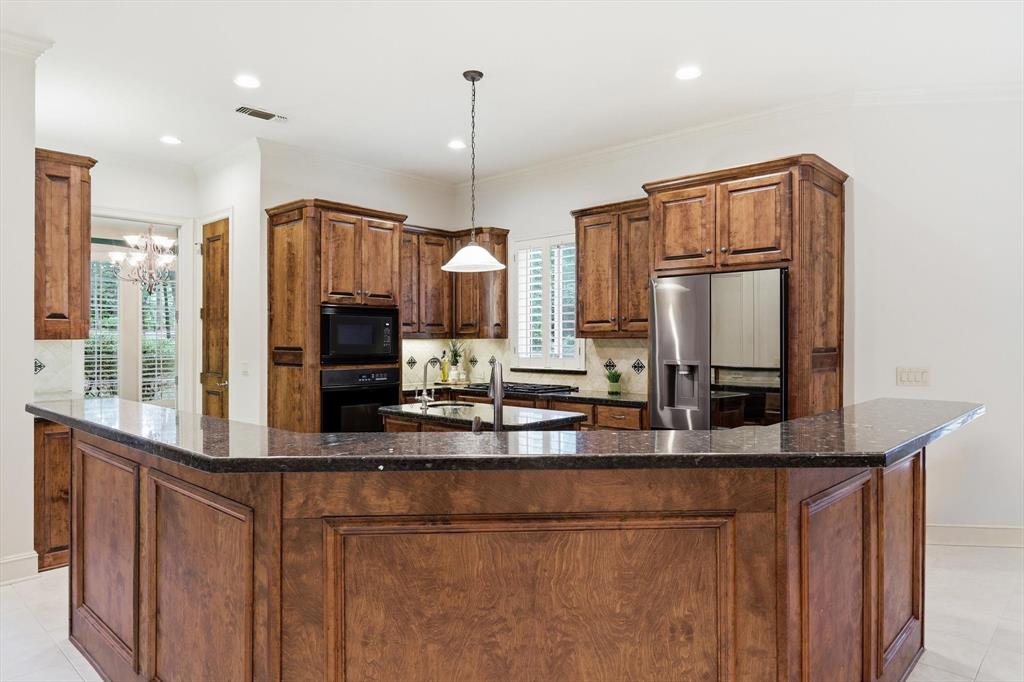 970 Crystal Cove Oak Point, TX 75068 - Photo 11 of 40 a kitchen with kitchen island granite countertop a refrigerator a sink and wooden cabinets