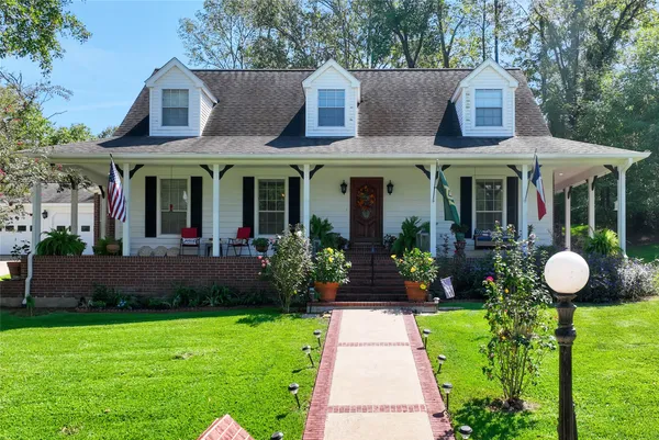 a view of a house with a small yard plants and a large tree
