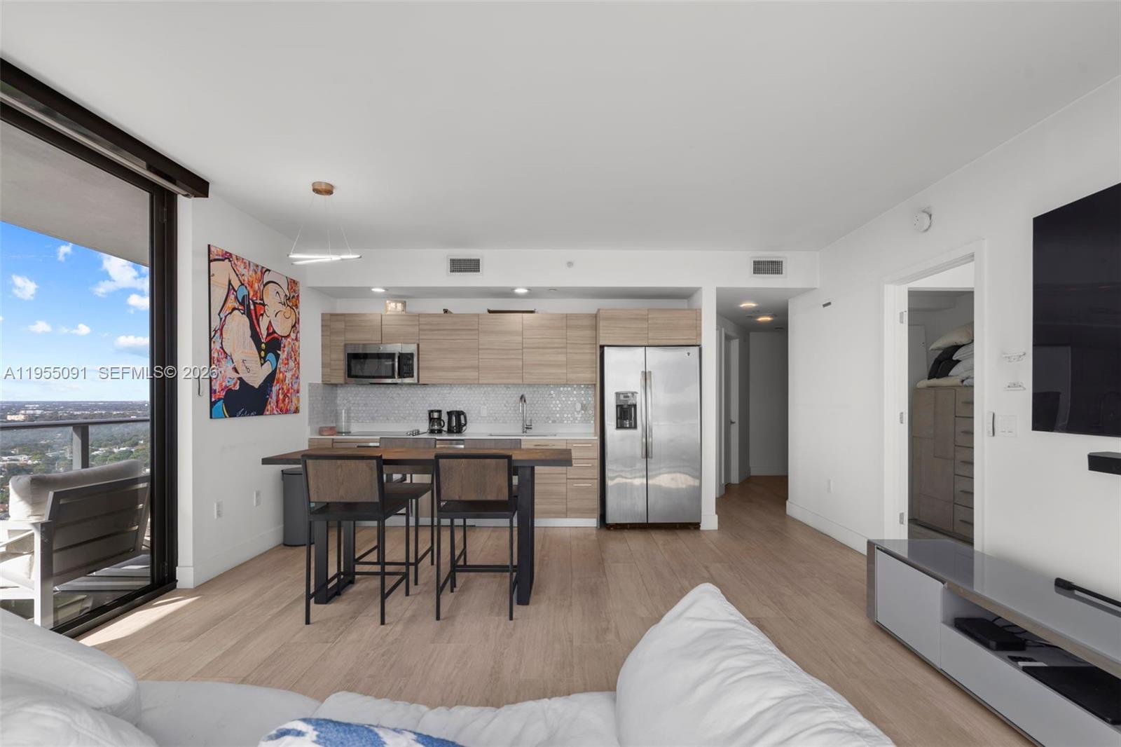 121 Northeast 34th Street, Unit 3001 Miami, FL 33137 - Photo 2 of 13 a living room with stainless steel appliances furniture a rug and a kitchen view