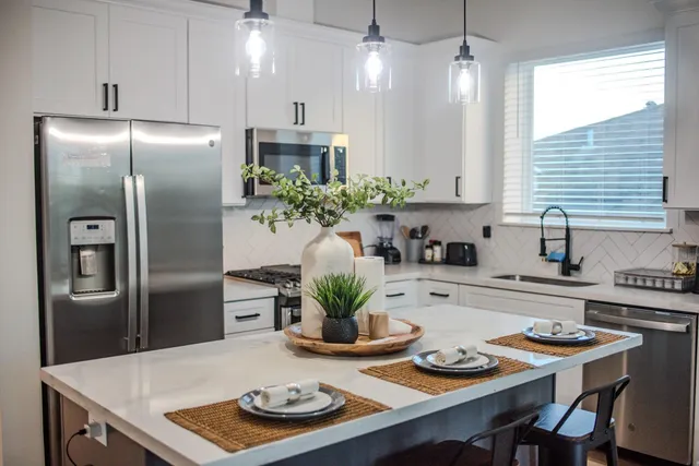 a kitchen with stainless steel appliances granite countertop a table chairs stove and refrigerator