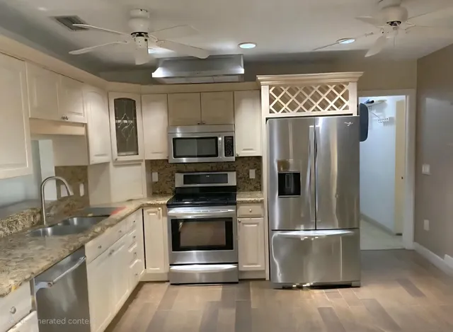 a kitchen with stainless steel appliances granite countertop a refrigerator a stove and a sink