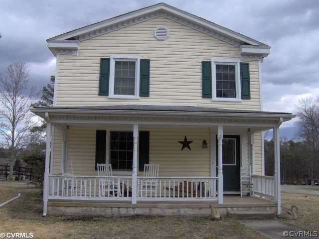 a view of a house with a small yard and large tree