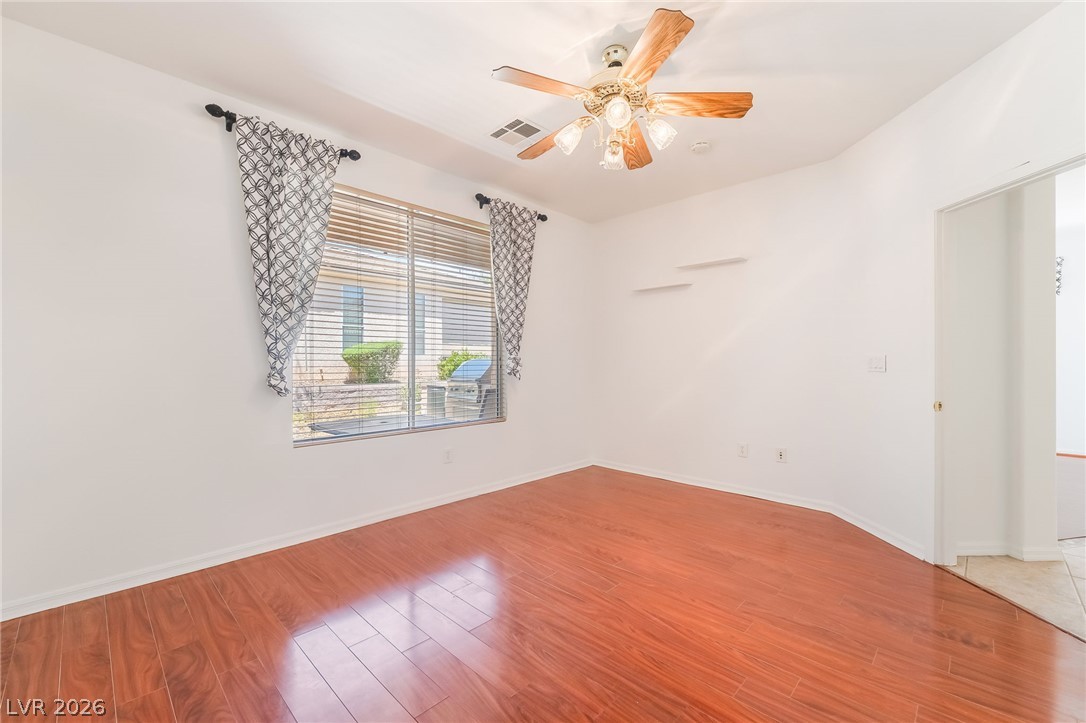 5389 Progresso Street Las Vegas, NV 89135 - Photo 21 of 41 Rich hardwood flooring complements a room illuminated by natural light, featuring a wood ceiling fan for comfort.