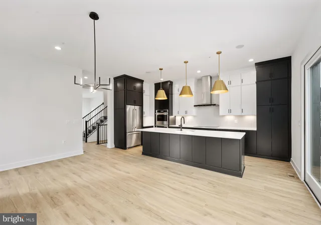 a large kitchen with stainless steel appliances kitchen island granite countertop a refrigerator a stove and a sink with wooden floor