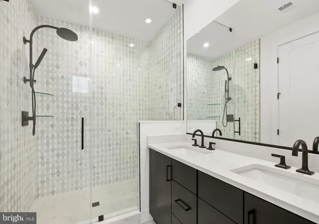 a bathroom with a double sink shower and a mirror