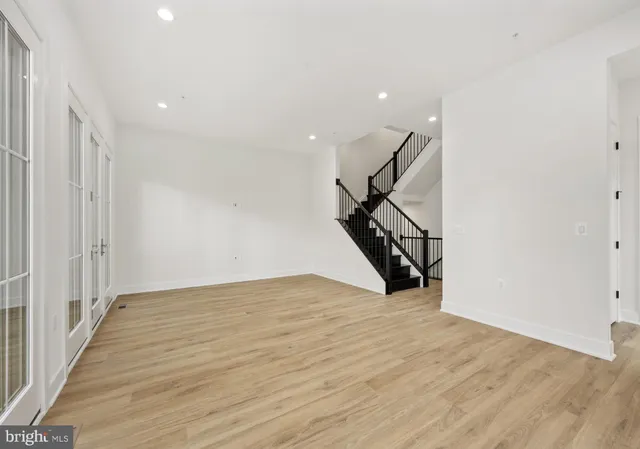 a view of an empty room with wooden floor and stairs