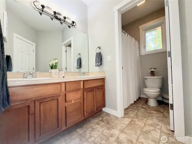 a spacious bathroom with a double vanity sink a mirror and a toilet