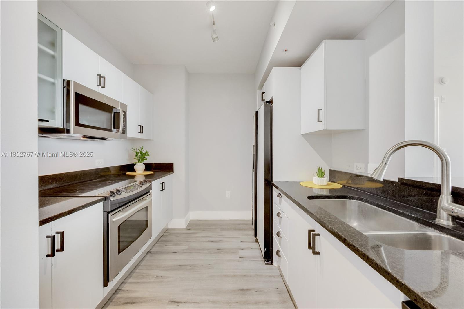 2775 Northeast 187th Street, Unit 309 Aventura, FL 33180 - Photo 3 of 21 a kitchen with granite countertop a sink stainless steel appliances and cabinets
