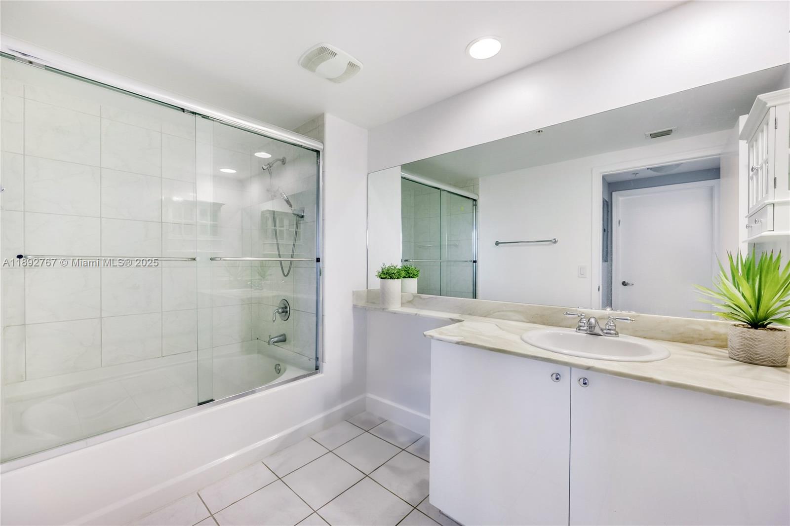 2775 Northeast 187th Street, Unit 309 Aventura, FL 33180 - Photo 10 of 21 a bathroom with a granite countertop sink a mirror and a bathtub