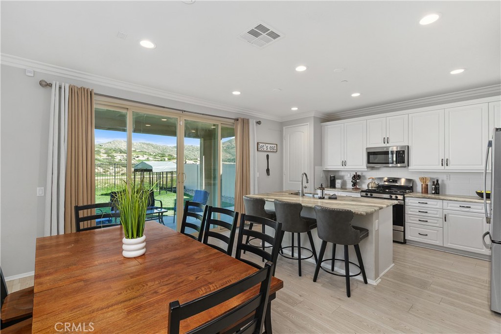 3056 Eveningcloud Street Hemet, CA 92543 - Photo 6 of 48 a kitchen with stainless steel appliances granite countertop a stove top oven a dining table and chairs with wooden floor