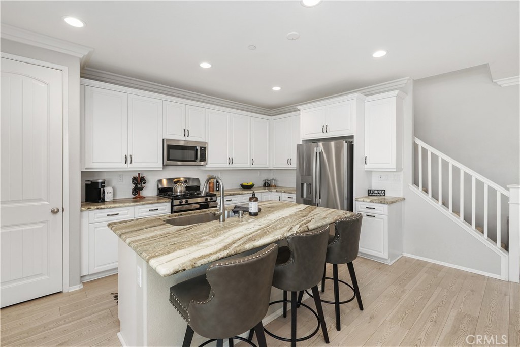 3056 Eveningcloud Street Hemet, CA 92543 - Photo 8 of 48 a kitchen with stainless steel appliances granite countertop a refrigerator a stove a microwave oven a sink with island and chairs