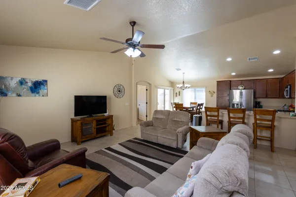 a living room with furniture a flat screen tv and kitchen view