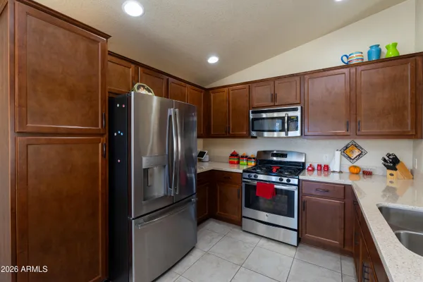 a kitchen with stainless steel appliances granite countertop a refrigerator a stove a sink a dining table and chairs