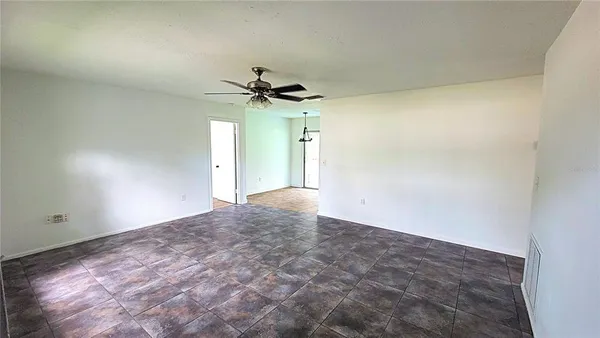 an empty room with a windows and a ceiling fan