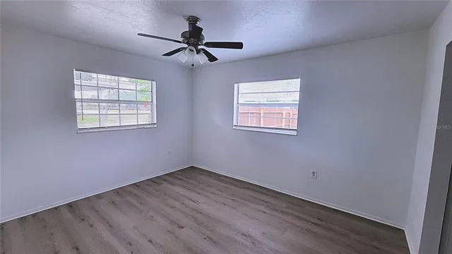a view of empty room with wooden floor and fan