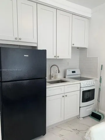 a kitchen with granite countertop white cabinets and sink