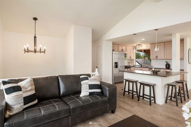 a living room with furniture kitchen view and a wooden floor