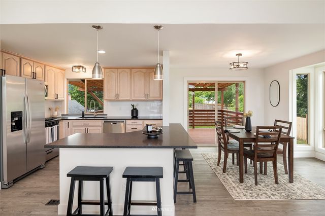 a kitchen with granite countertop a table chairs microwave and cabinets