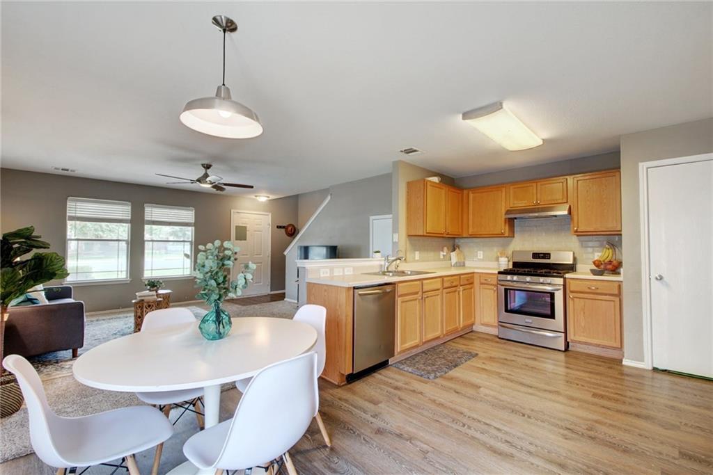 13905 Briarcreek Loop Manor, TX 78653 - Photo 23 of 25 Kitchen featuring light countertops, stainless steel appliances, open floor plan, pendant lighting, and light wood-style flooring