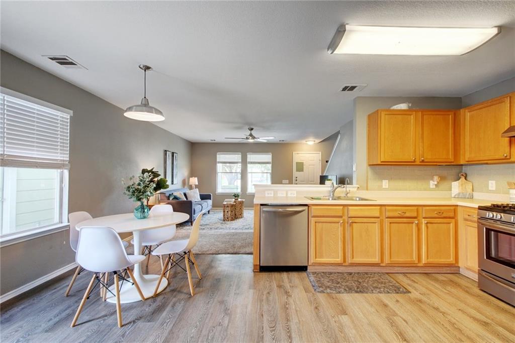13905 Briarcreek Loop Manor, TX 78653 - Photo 24 of 25 Kitchen with light countertops, open floor plan, stainless steel appliances, light wood finished floors, and hanging light fixtures