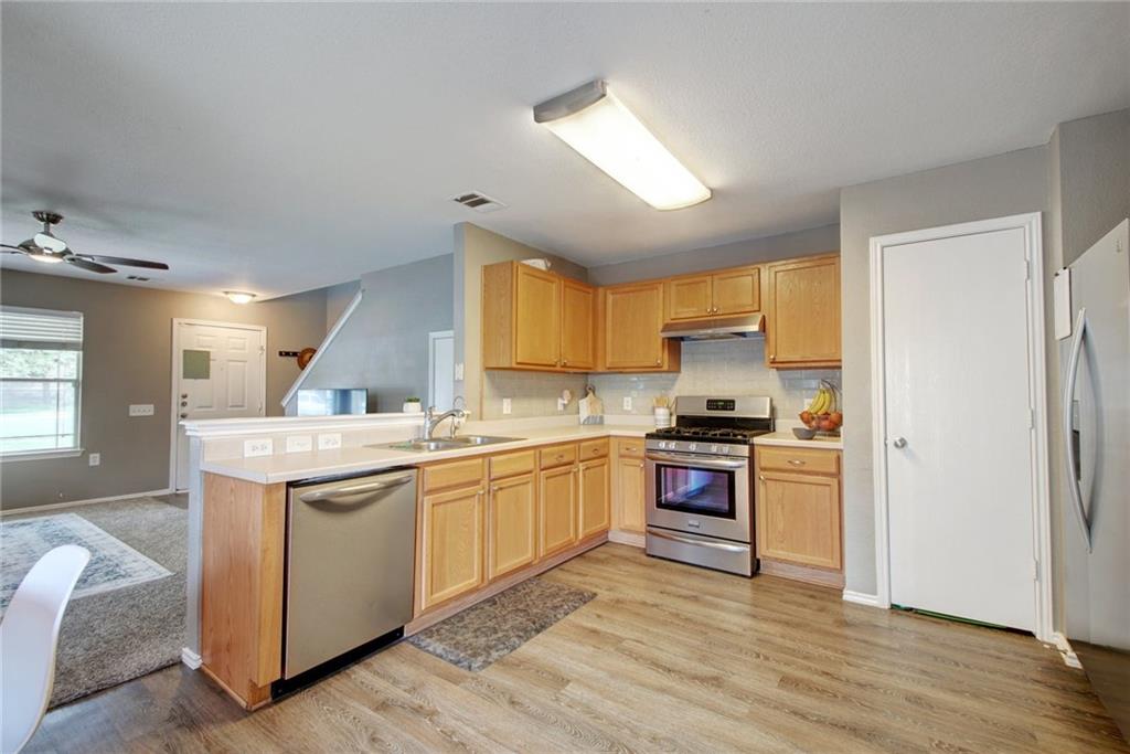 13905 Briarcreek Loop Manor, TX 78653 - Photo 25 of 25 Kitchen featuring stainless steel appliances, light countertops, a ceiling fan, open floor plan, and light wood finish cabinets