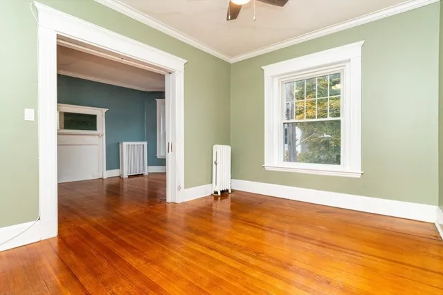 a view of an empty room with wooden floor and a window