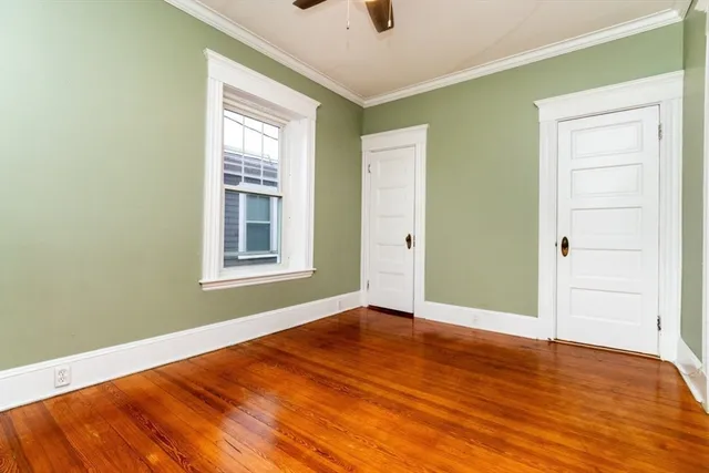 an empty room with wooden floor cabinet and windows