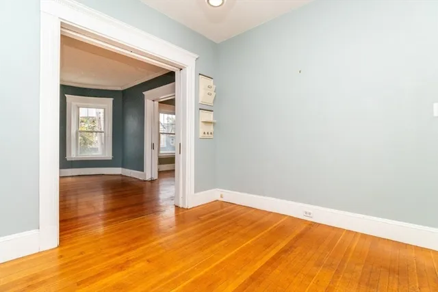 a view of empty room with wooden floor and fan