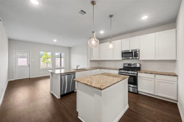 a kitchen with stainless steel appliances granite countertop hardwood floor sink stove and wooden floor