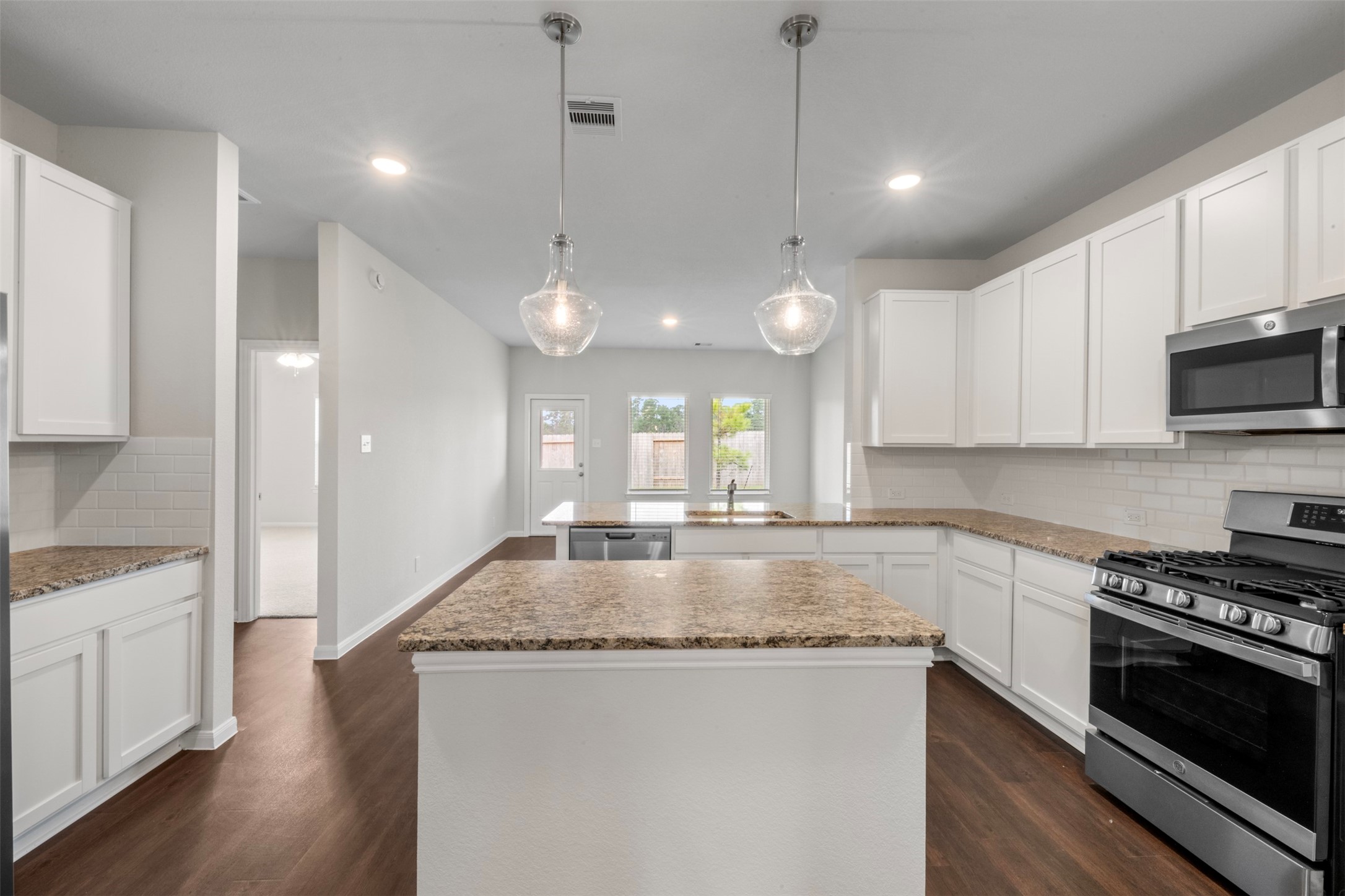10783 Sora Drive Willis, TX 77378 - Photo 8 of 26 a kitchen with kitchen island granite countertop a stove a sink a refrigerator and white cabinets with wooden floor