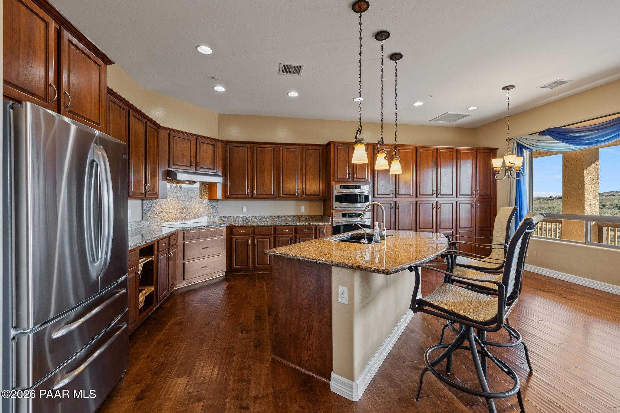 15411 East Rough Rider Ridge Mayer, AZ 86333 - Photo 14 of 57 a kitchen with stainless steel appliances kitchen island granite countertop a refrigerator a stove top oven a sink dishwasher and chairs with wooden floor
