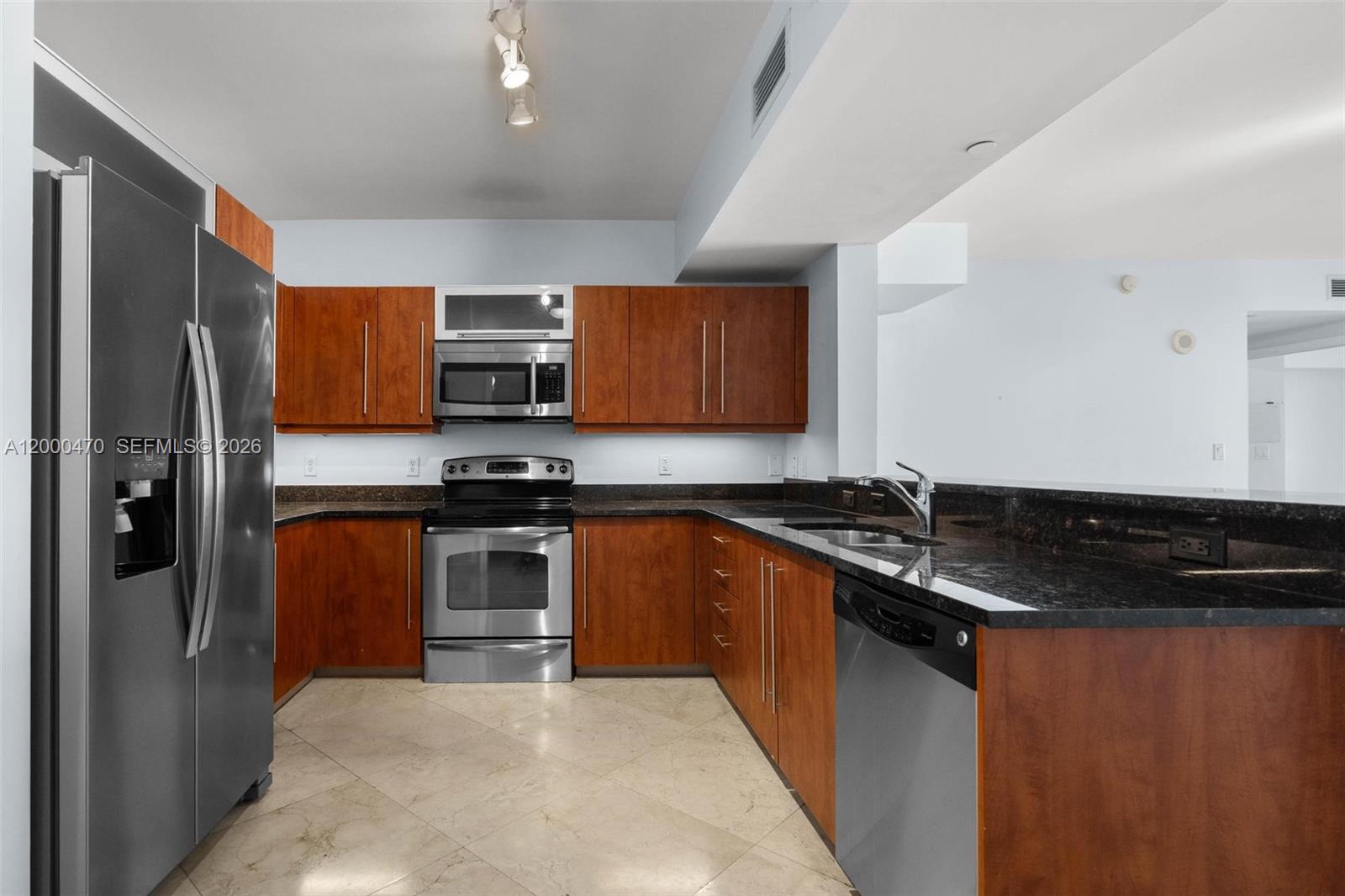 7350 Southwest 89th Street, Unit 1707S Miami, FL 33156 - Photo 36 of 45 a kitchen with granite countertop stainless steel appliances and wooden cabinets