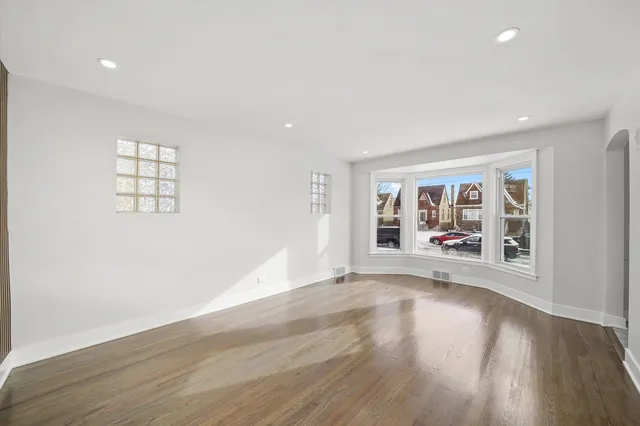 a view of empty room with wooden floor fan and window