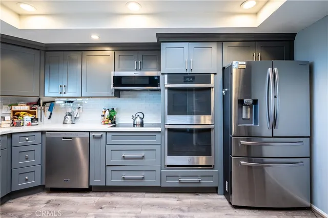 a kitchen with stainless steel appliances granite countertop a refrigerator and a stove top oven