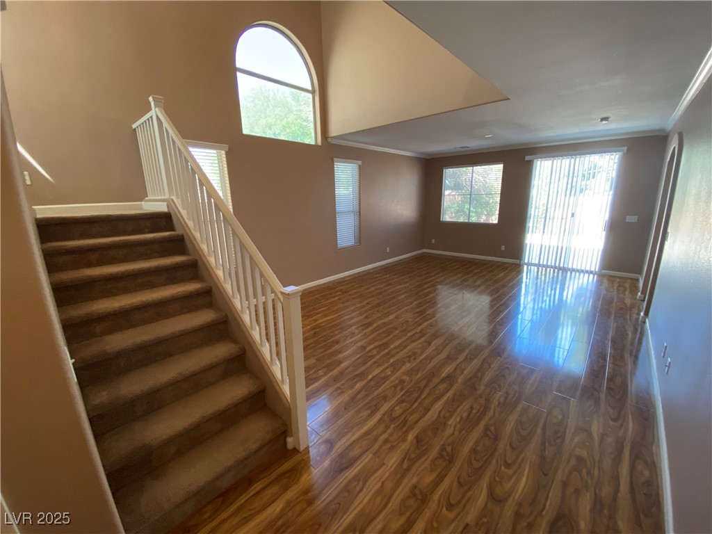 5680 Arrow Tree Street Las Vegas, NV 89130 - Photo 14 of 27 Unfurnished living room with dark wood-style floors, stairway, crown molding, and a high ceiling
