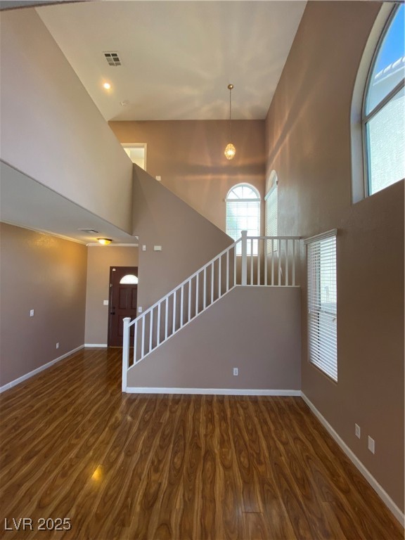 5680 Arrow Tree Street Las Vegas, NV 89130 - Photo 15 of 27 Unfurnished living room with a high ceiling, dark wood-type flooring, and stairway