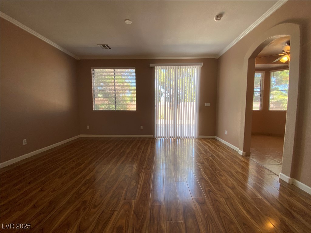 5680 Arrow Tree Street Las Vegas, NV 89130 - Photo 9 of 27 Spare room with arched walkways, ornamental molding, ceiling fan, and dark wood-style flooring