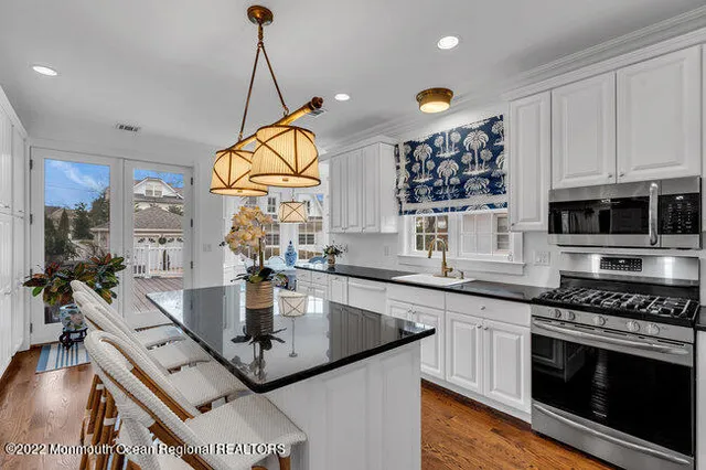 a kitchen with stainless steel appliances granite countertop a sink a stove and a wooden floors