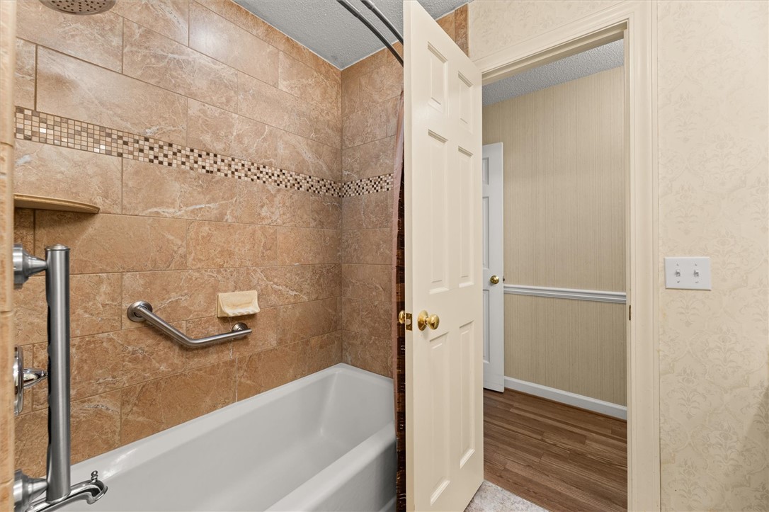 105 Hamilton Drive Anderson, SC 29621 - Photo 42 of 49 This bathroom features a sleek tiled shower and a crisp white tub, offering a clean and functional design.