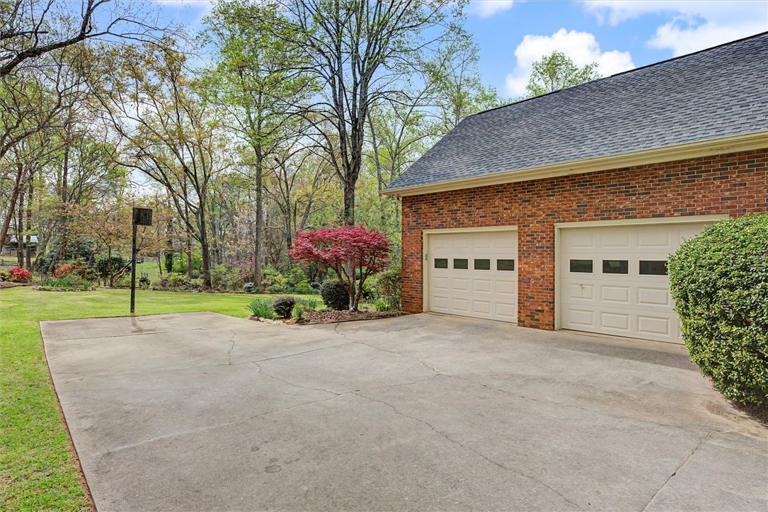105 Hamilton Drive Anderson, SC 29621 - Photo 6 of 49 This residence features a spacious driveway and a two-car garage, complemented by mature trees and landscaping.