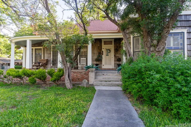 a front view of a house with a yard and large tree