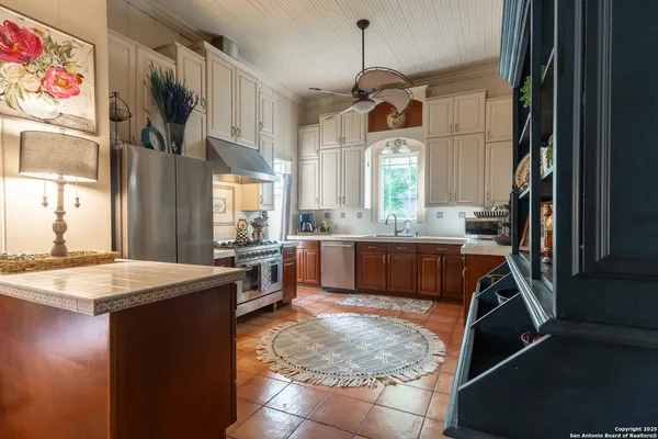 a kitchen with kitchen island granite countertop wooden cabinets a stove a sink and a window