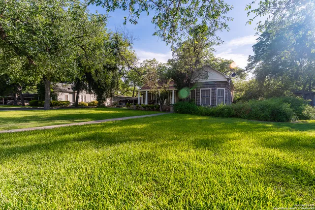 a view of a house with a big yard and large trees
